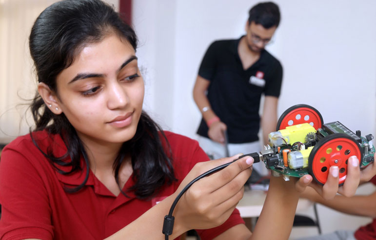 The image with a blurred background shows the students of chitkara university, one in black t-shirts and one in red, working on their projects.
