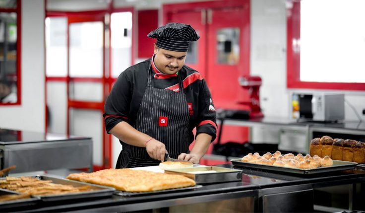 Students practicing Baking and Patisserie techniques in a professional kitchen, learning from expert chefs.