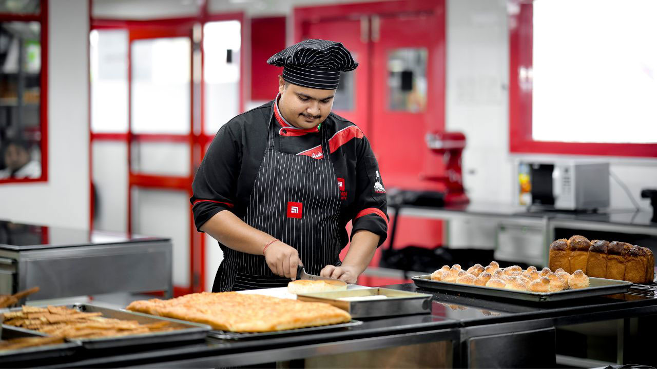 Students practicing Baking and Patisserie techniques in a professional kitchen, learning from expert chefs.