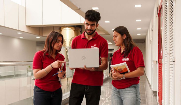 Three students collaborating on laptops in a modern classroom, representing Digital Marketing BBA in Punjab.