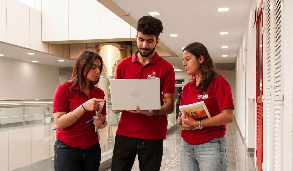 Three students collaborating on laptops in a modern classroom, representing Digital Marketing BBA in Punjab.