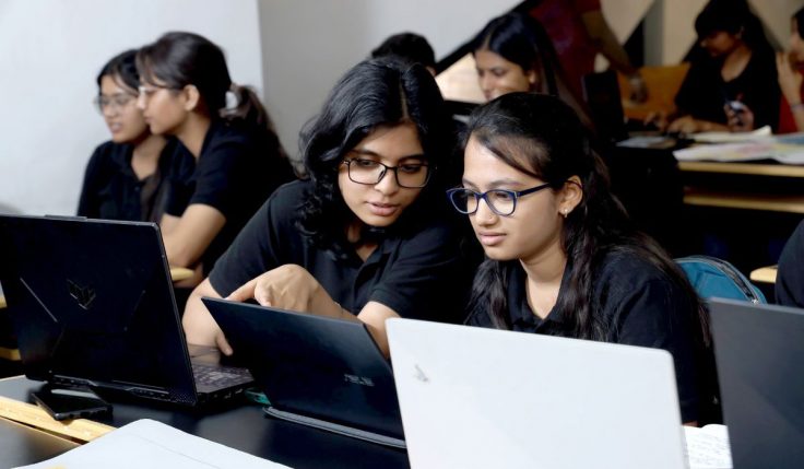 Students learning UI and UX design concepts while working on laptops for a career in UI/UX design in India