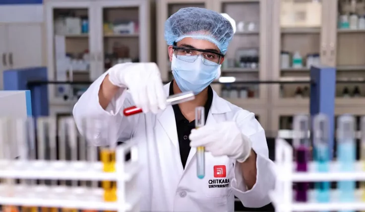Chitkara University pharmacy student examining test tubes while researching B. Pharmacy Course Fees in India and lab facilities