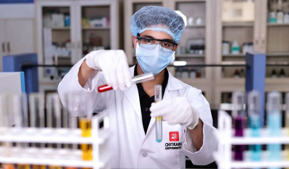 Chitkara University pharmacy student examining test tubes while researching B. Pharmacy Course Fees in India and lab facilities